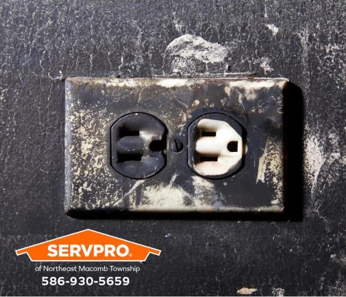 An electrical outlet is covered with soot.