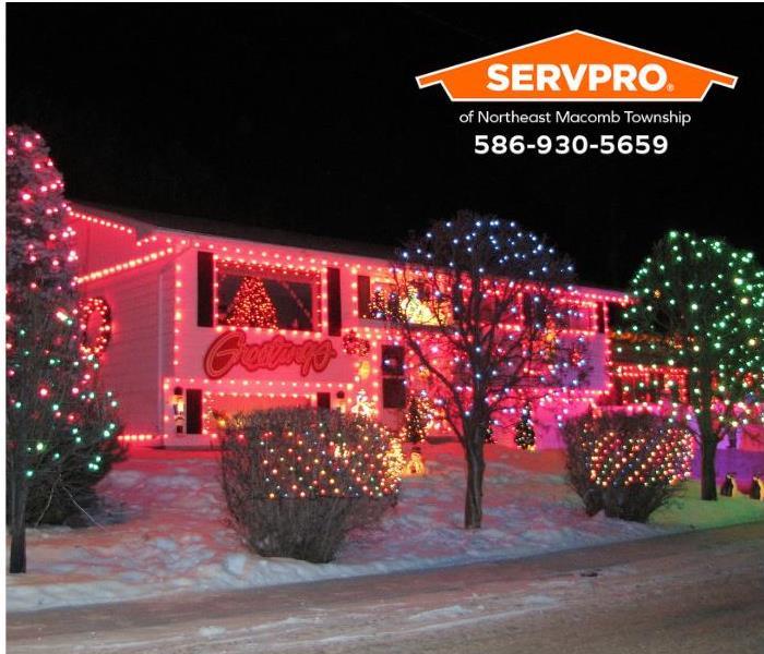 Festive holiday lights adorn a house and landscape trees and shrubbery. 